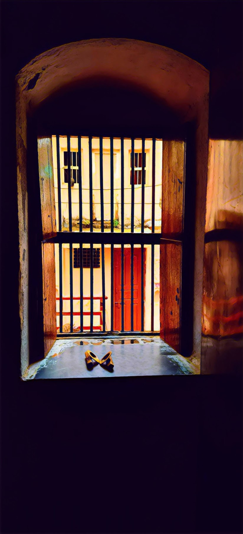 A barred doorway with a pair of footwear in the light