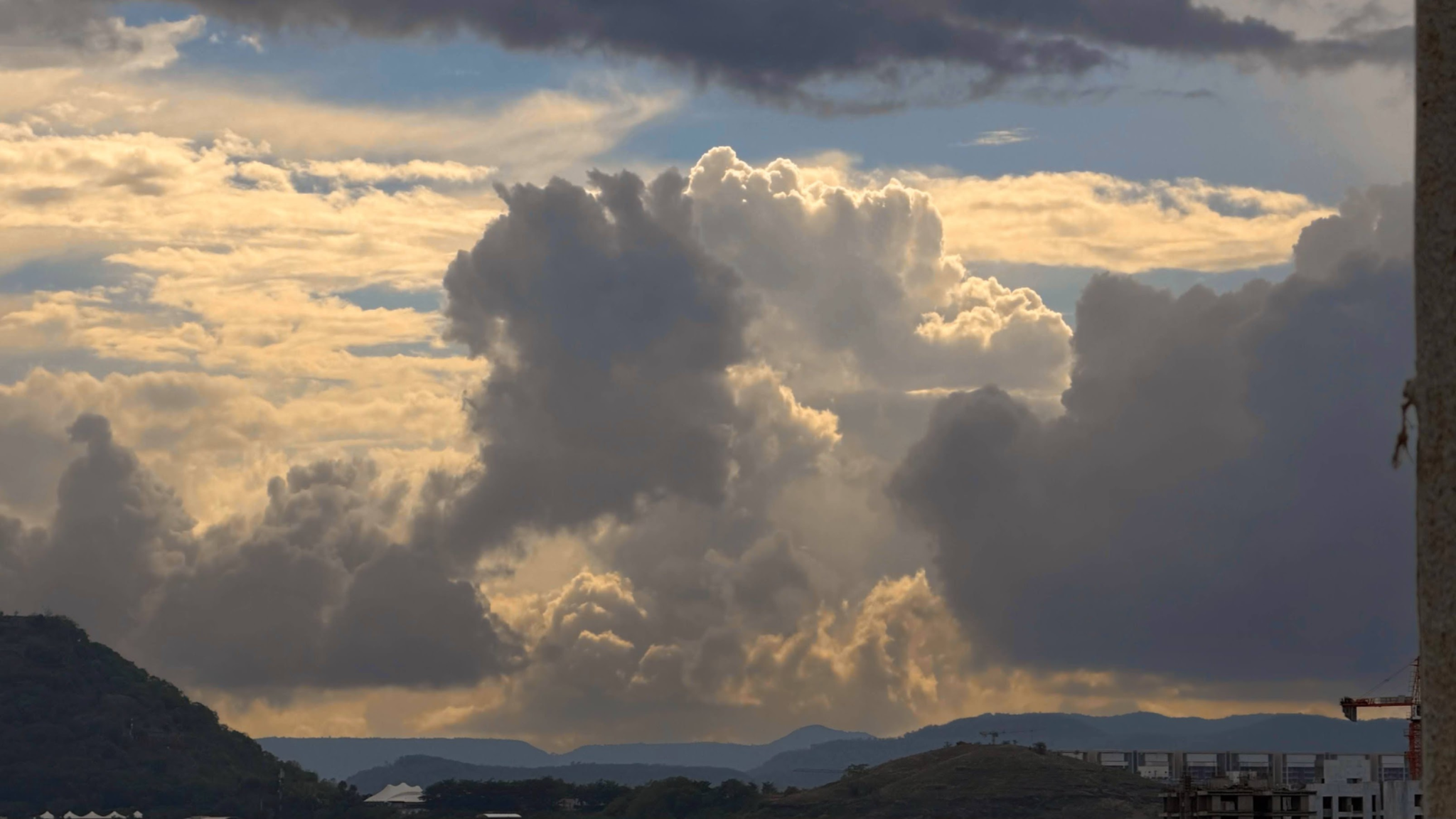 Monumental clouds rising over distant hills